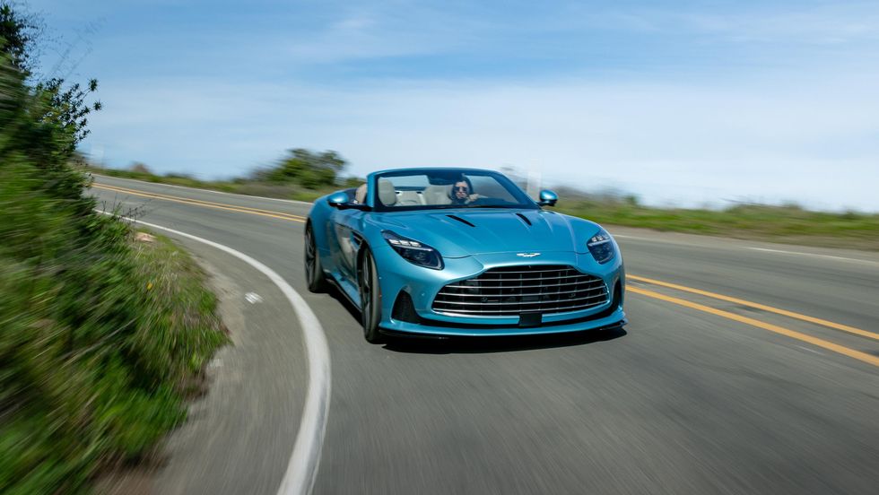 Ein blauer Aston Martin DB12 Volante fährt eine Straße entlang